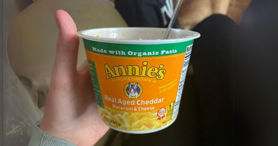 Annie's Real Aged Cheddar Microwavable Mac & Cheese 2.01oz in hand with spoon it