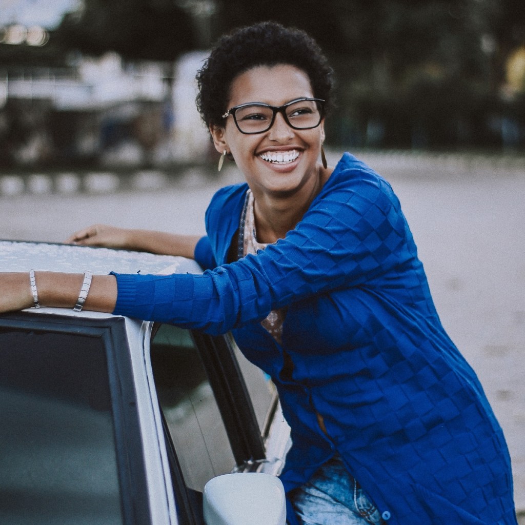 young woman in blue shirt outside of car - good grades report card